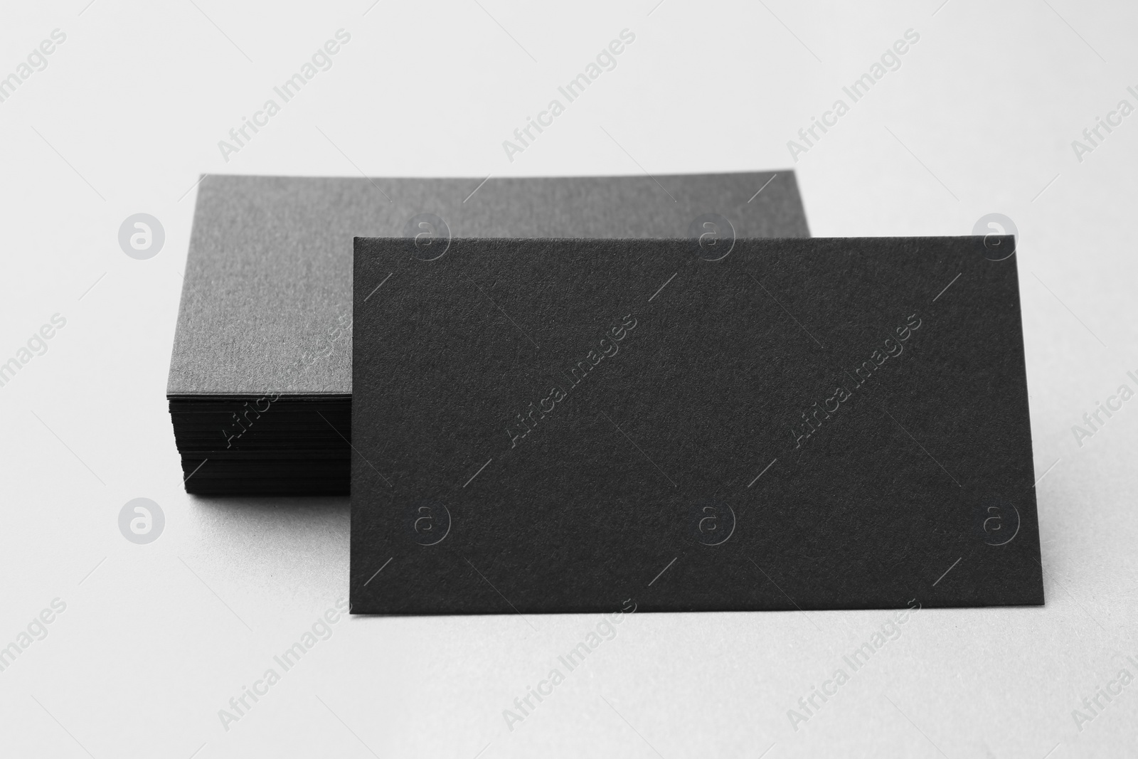 Photo of Blank black business cards on white table, closeup. Mockup for design