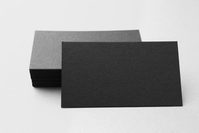 Blank black business cards on white table, closeup. Mockup for design