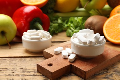 Photo of Dietary supplements. Pills in bowls and food products on wooden table