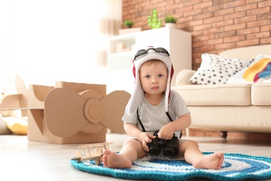 Adorable little child playing with binoculars at home