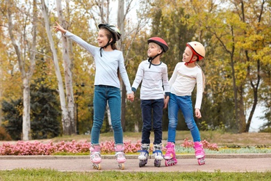 Photo of Happy children wearing roller skates in autumn park