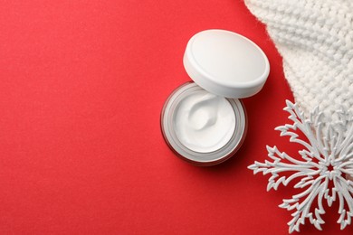 Photo of Winter skin care. Flat lay composition with hand cream and decorative snowflake on red background. Space for text
