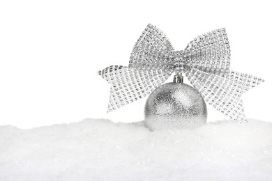 Beautiful silver Christmas ball with bow on snow against white background