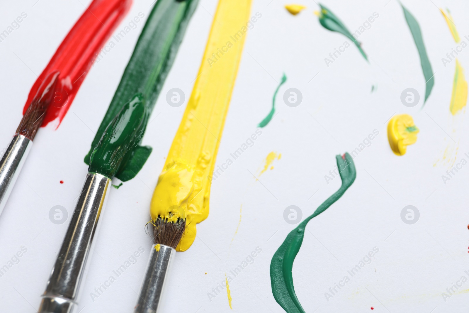 Photo of Brushes with different paints and strokes on white background, closeup