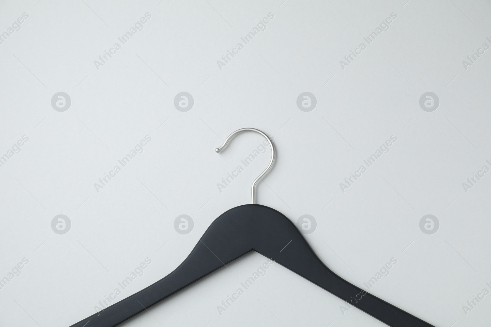 Photo of Empty black hanger on light grey background, top view. Space for text