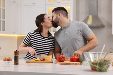 Photo of Lovely couple kissing while cooking in kitchen