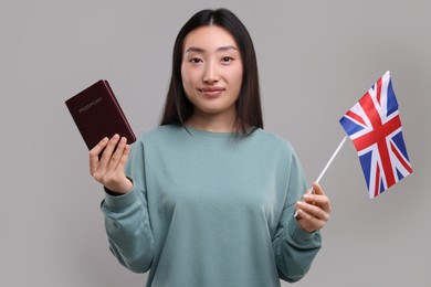 Immigration to United Kingdom. Woman with passport and flag on grey background