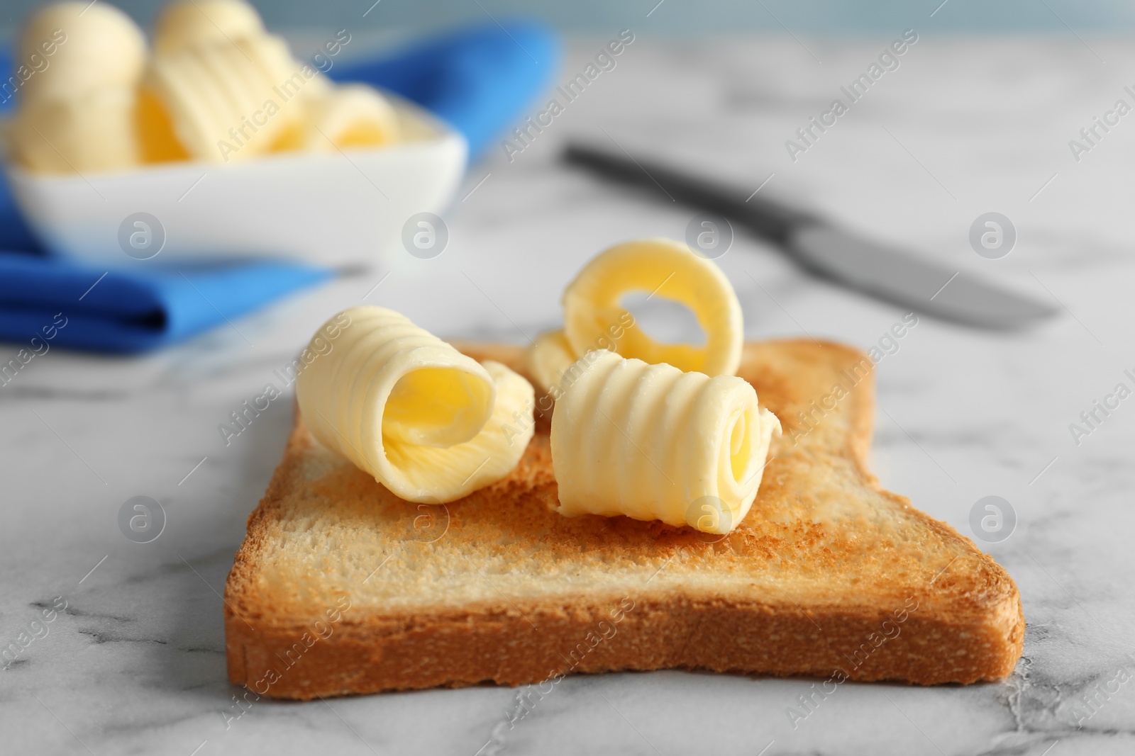 Photo of Toasted bread with butter curls on table