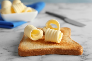 Photo of Toasted bread with butter curls on table