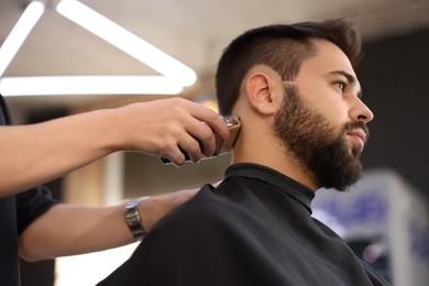 Photo of Professional hairdresser working with client in barbershop, low angle view