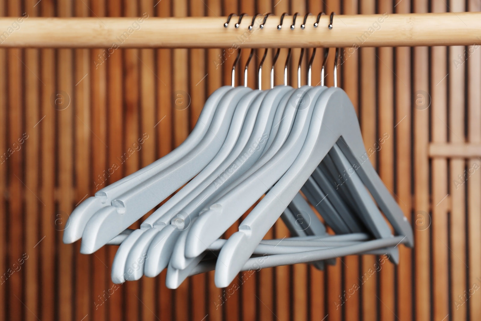 Photo of Empty hangers on rail against wooden background