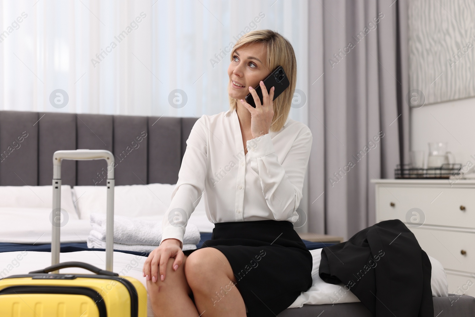 Photo of Smiling businesswoman talking on smartphone in stylish hotel room