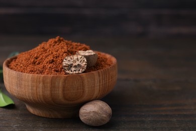 Nutmeg powder and halves of seed in bowl on wooden table