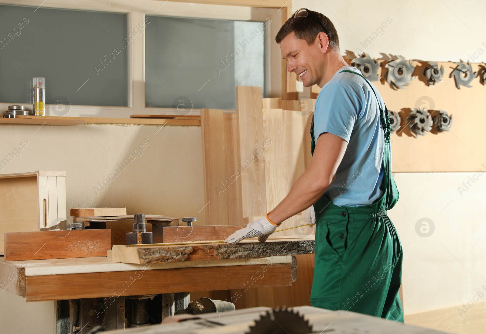 Photo of Professional carpenter measuring wooden board in workshop