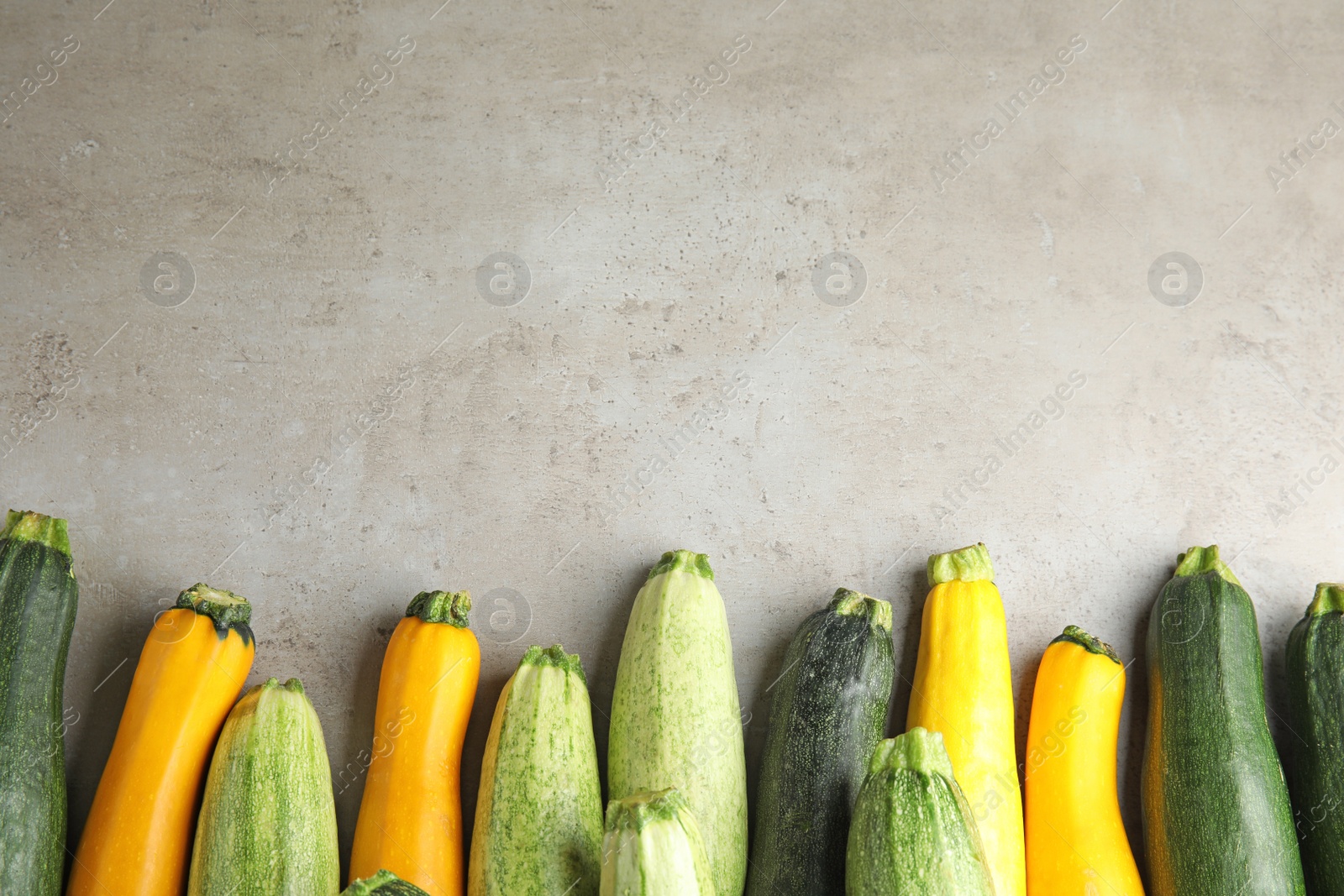 Photo of Fresh ripe zucchinis on grey table, flat lay. Space for text