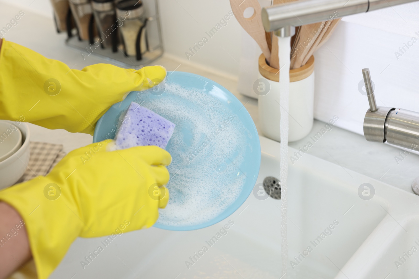 Photo of Man washing plate above sink in kitchen, closeup