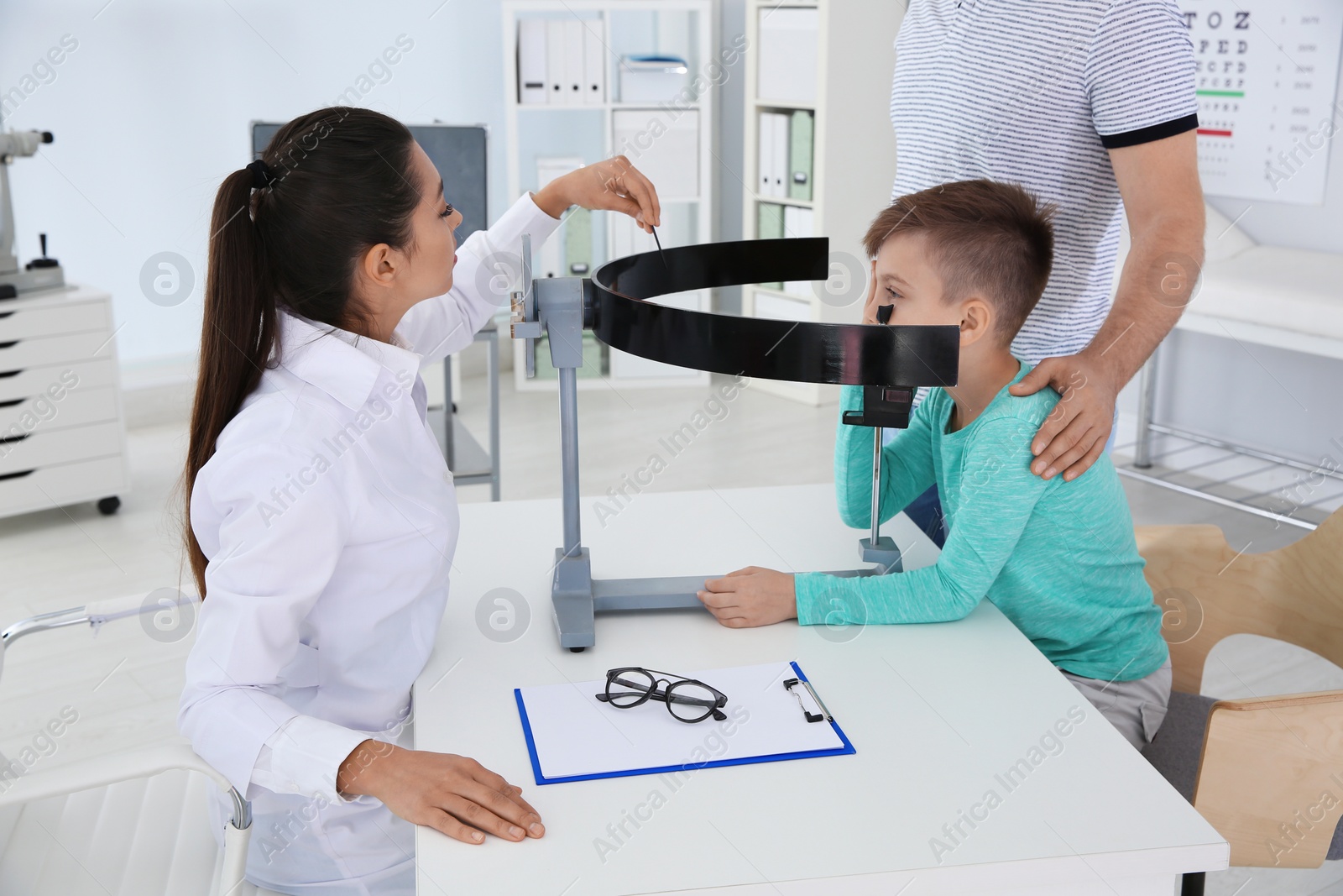 Photo of Children's doctor examining little boy's vision in clinic