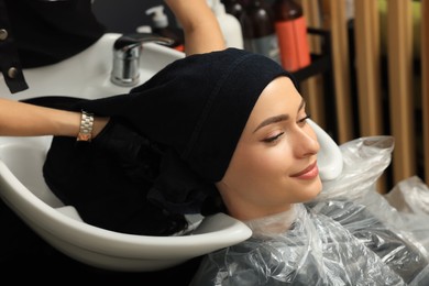 Hairdresser drying woman's hair with towel in beauty salon