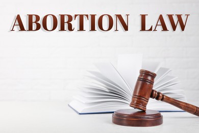 Image of Abortion law. Gavel and book on table against white background