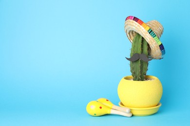 Mexican sombrero hat, cactus with fake mustache and maracas on light blue background, space for text