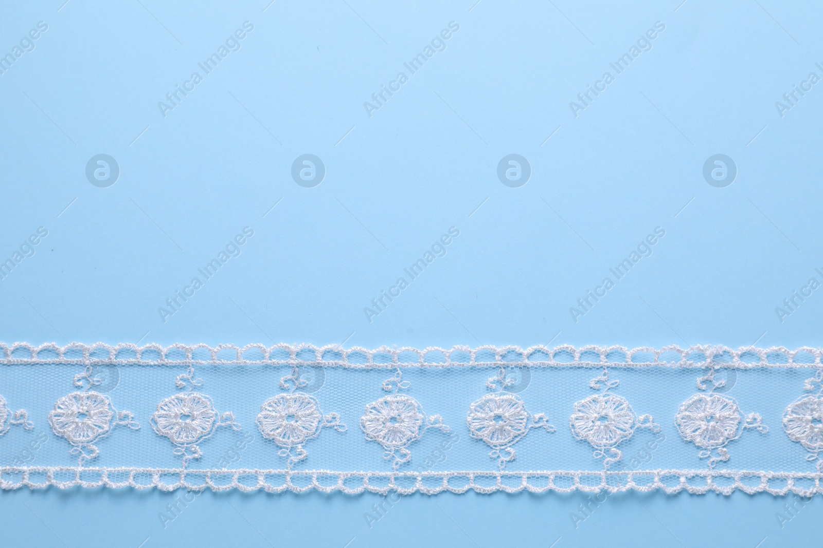 Photo of White lace on light blue background, top view. Space for text