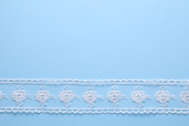 White lace on light blue background, top view. Space for text