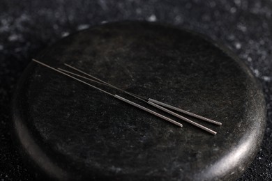 Acupuncture needles and spa stone on table, closeup