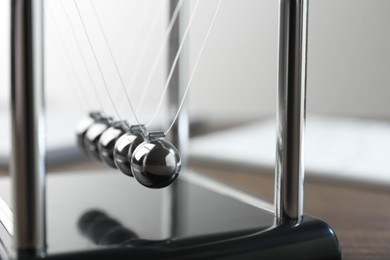 Newton's cradle on wooden table, closeup. Physics law of energy conservation