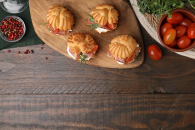 Delicious profiteroles and ingredients on wooden table, flat lay. Space for text