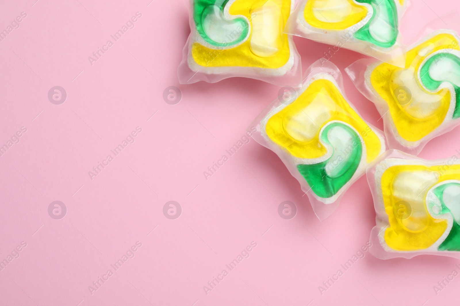 Photo of Many dishwasher detergent pods on pink background, flat lay. Space for text