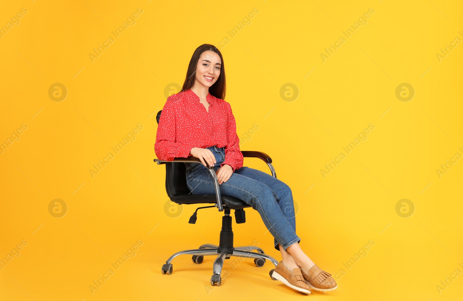 Photo of Young woman sitting in comfortable office chair on yellow background