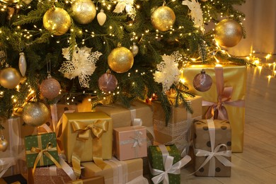 Many gift boxes under decorated Christmas tree at home