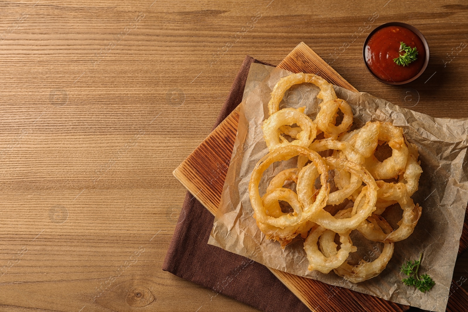 Photo of Flat lay composition with homemade crispy onion rings and tomato sauce on wooden background. Space for text