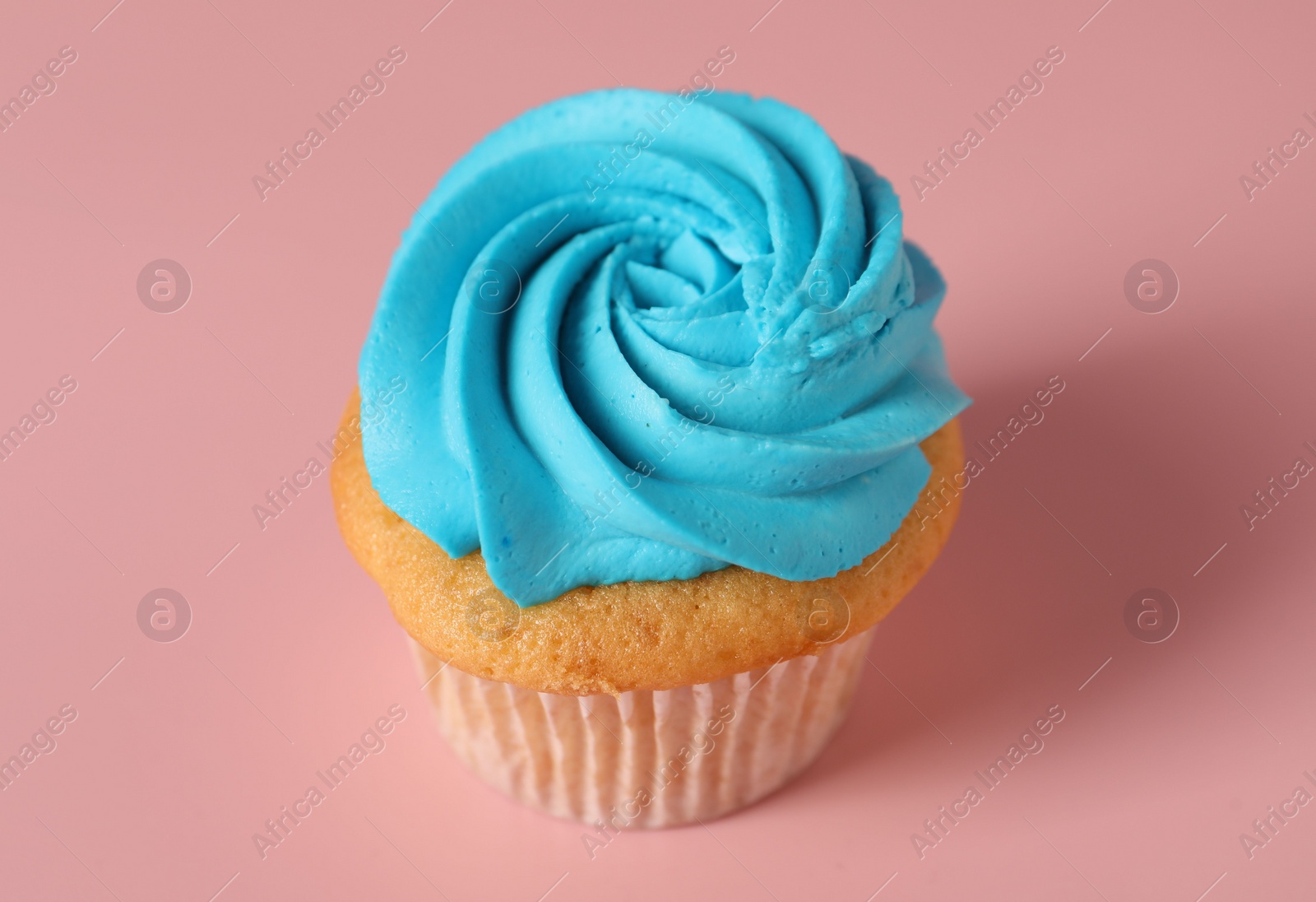 Photo of Delicious cupcake with bright cream on pink background, closeup