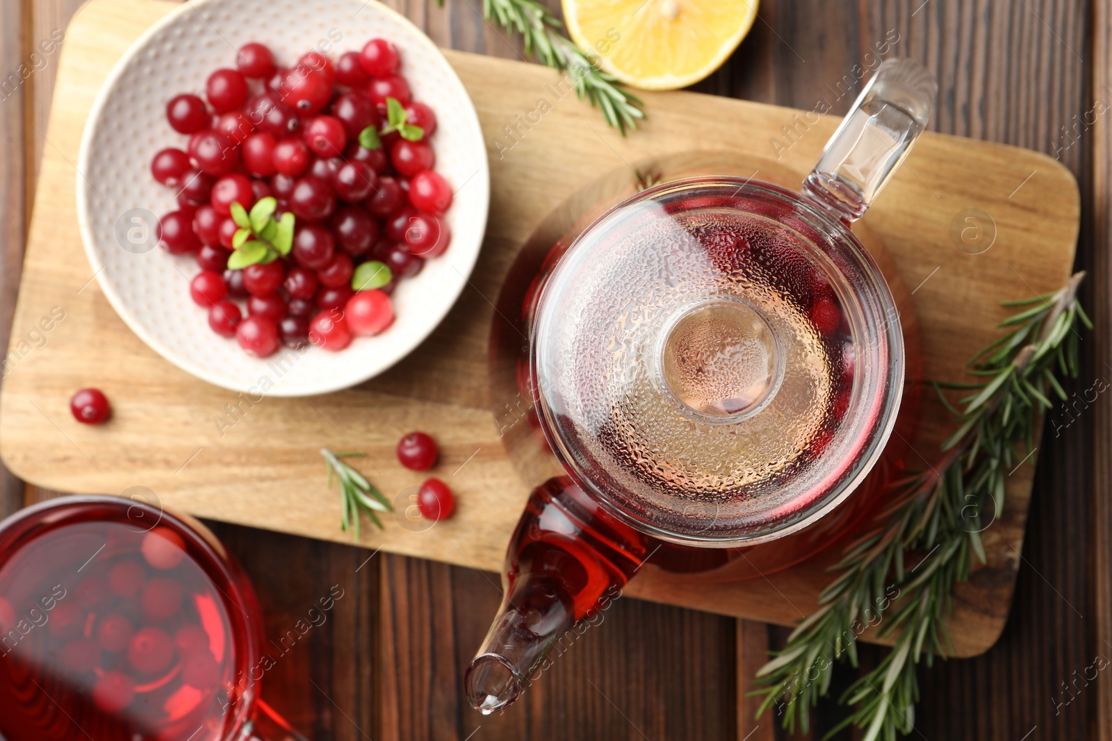 Photo of Tasty hot cranberry tea, rosemary and fresh berries on wooden table