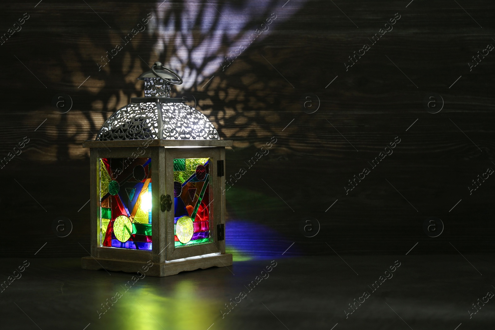 Photo of Decorative Arabic lantern on table against dark background. Space for text