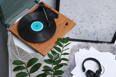 Photo of Stylish turntable with vinyl record on coffee table in room, above view