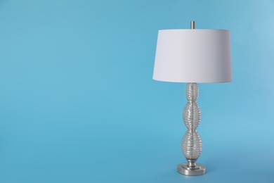 Photo of Stylish new night lamp on light blue background. Space for text