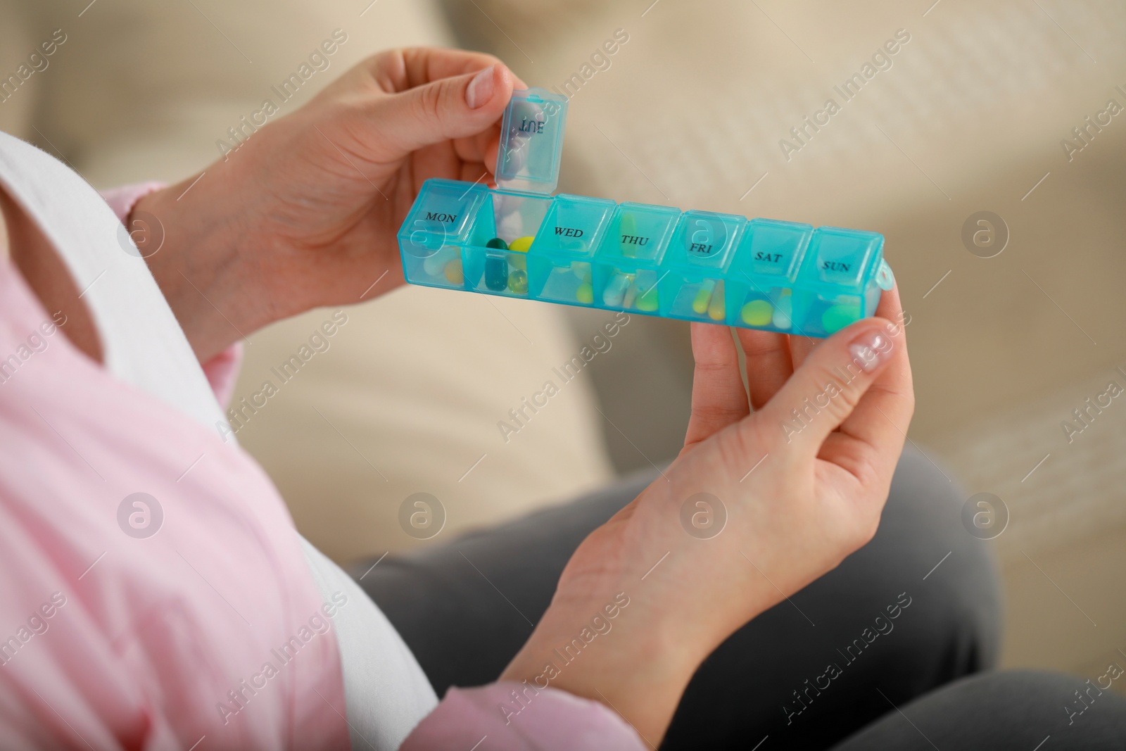 Photo of Pregnant woman holding box with pills on blurred background, closeup