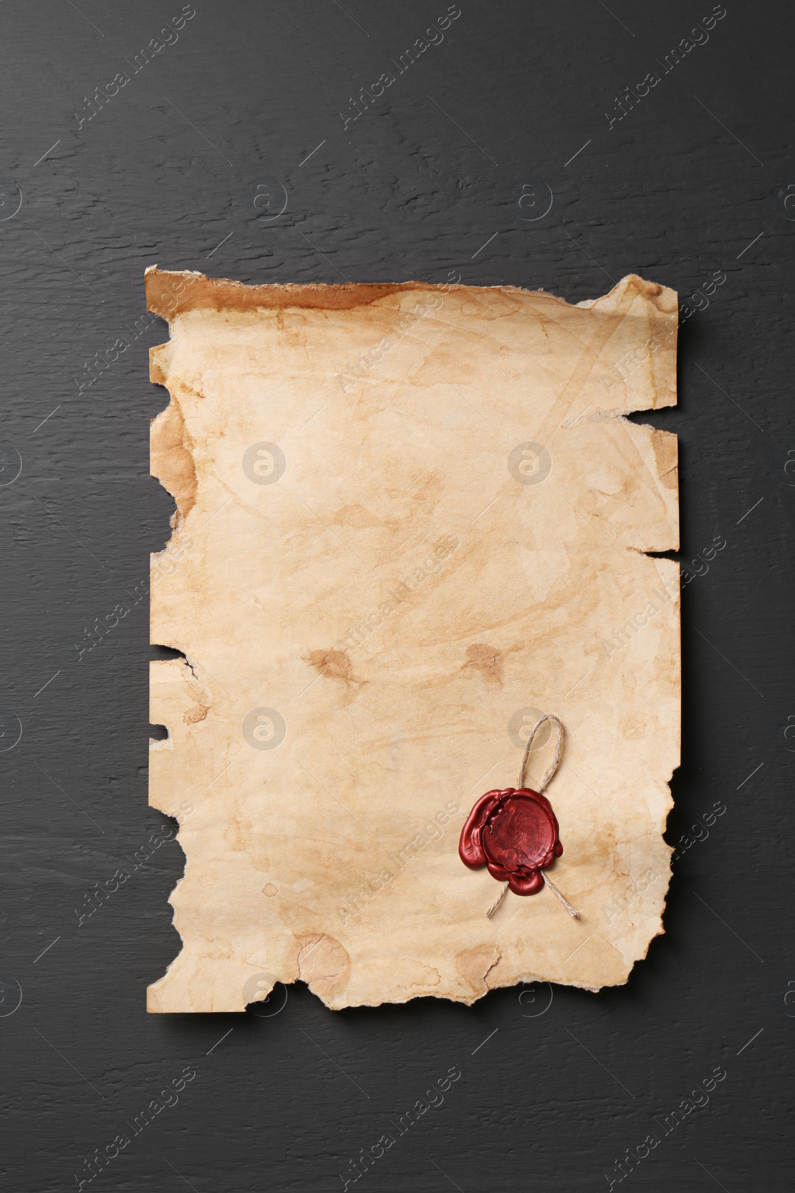 Photo of Sheet of old parchment paper with wax stamp on grey wooden table, top view. Space for text