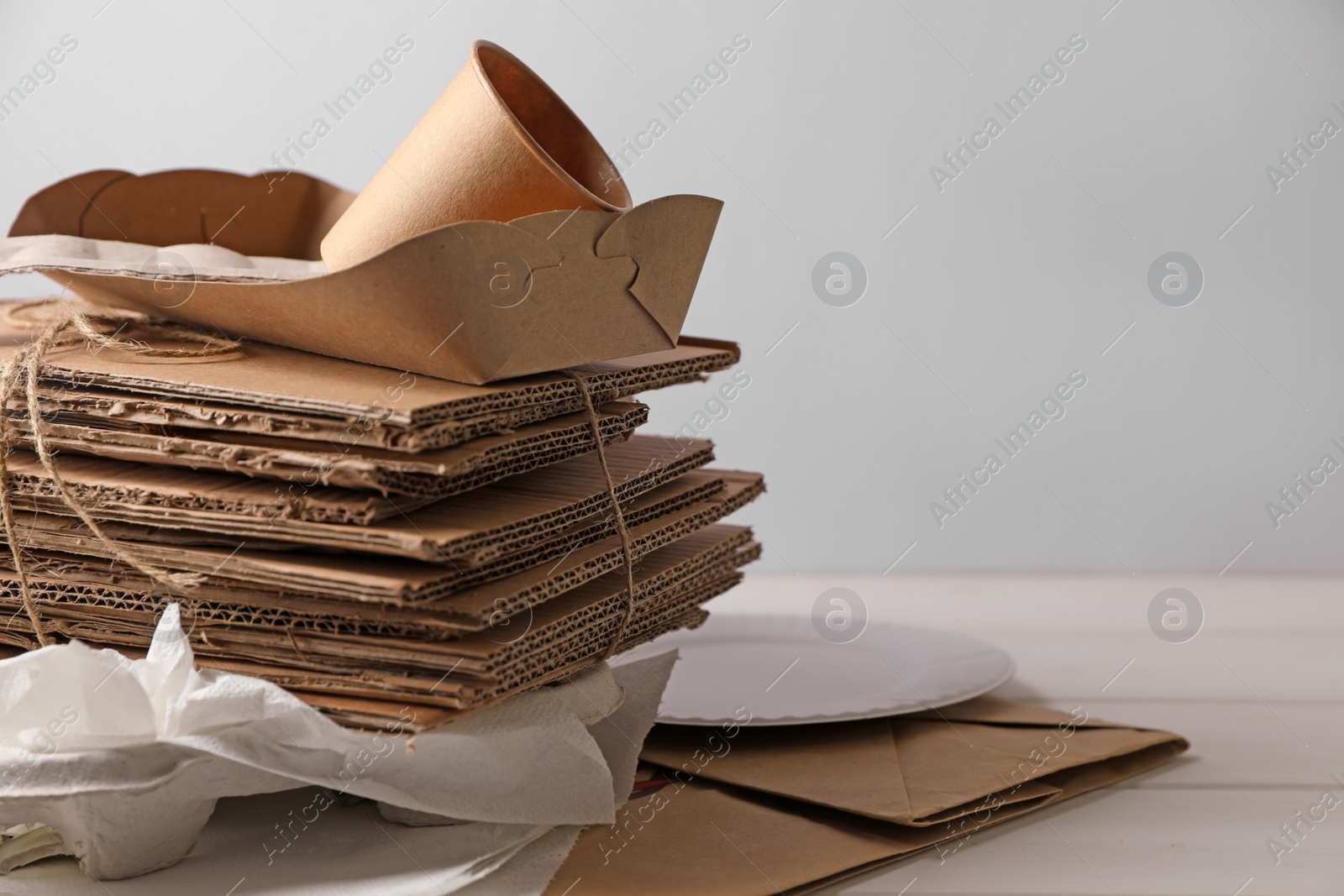 Photo of Heap of waste paper on white wooden table, space for text