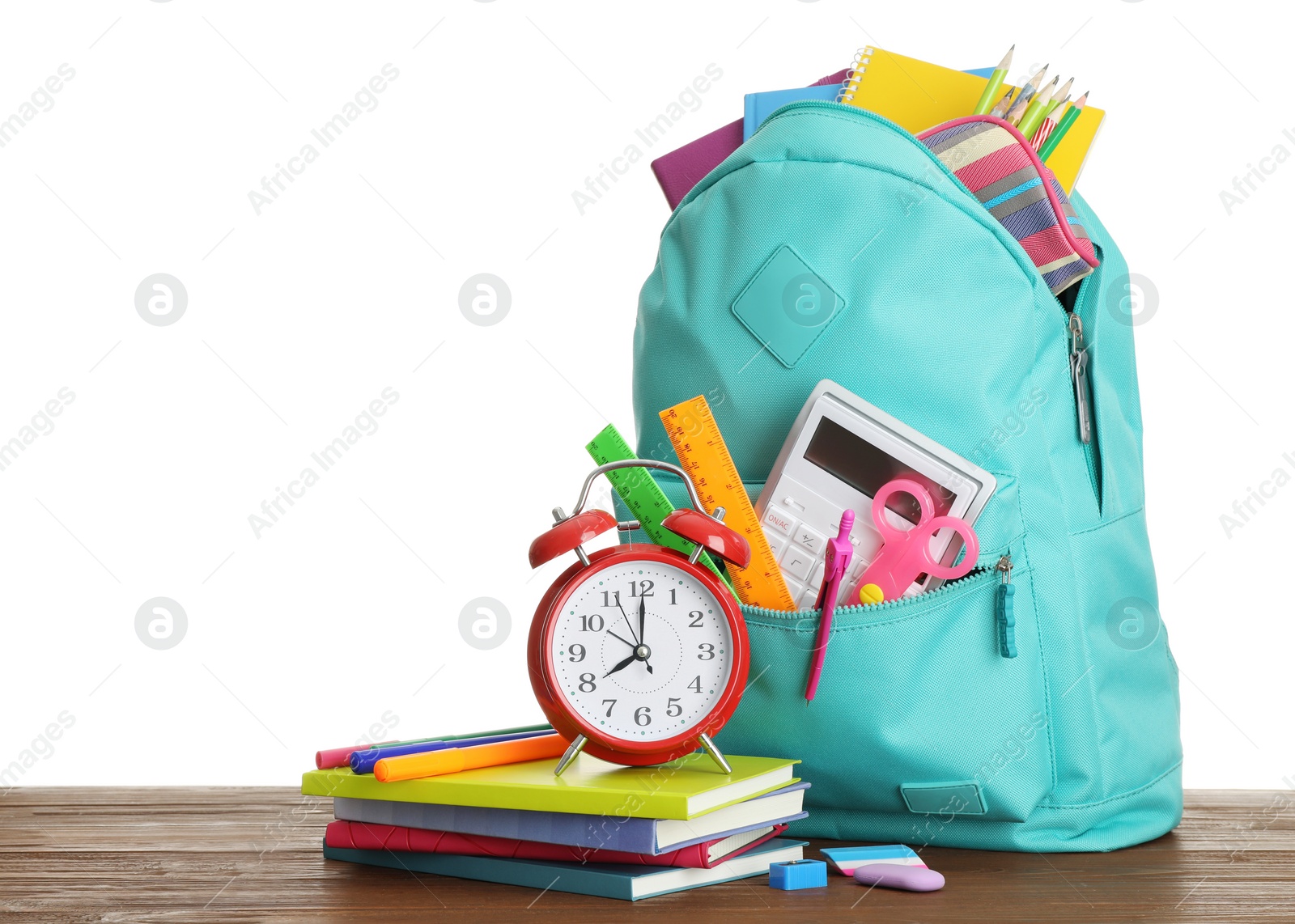 Photo of Stylish schoolbag with different stationary and alarm clock on wooden table, white background