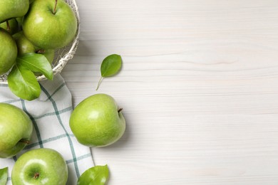 Photo of Fresh ripe green apples with leaves on white wooden table, flat lay. Space for text