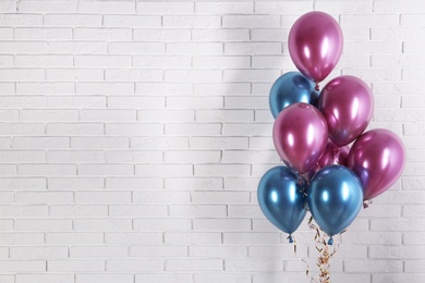 Photo of Bright colorful balloons near brick wall, space for text. Party time