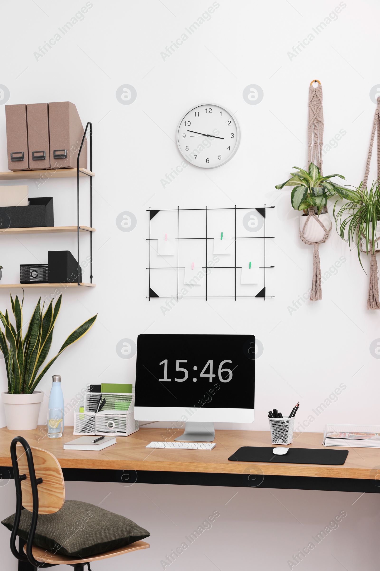 Photo of Cozy workplace with computer, modern furniture and houseplants at home