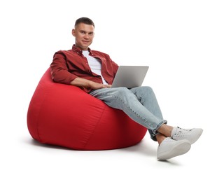 Photo of Man with laptop sitting on red bean bag chair against white background