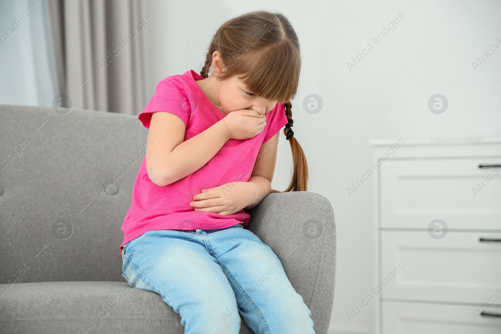 Photo of Little girl suffering from nausea in living room