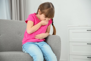 Photo of Little girl suffering from nausea in living room