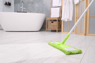 Image of Washing floor with mop in bathroom, space for text. Clean trace on dirty surface