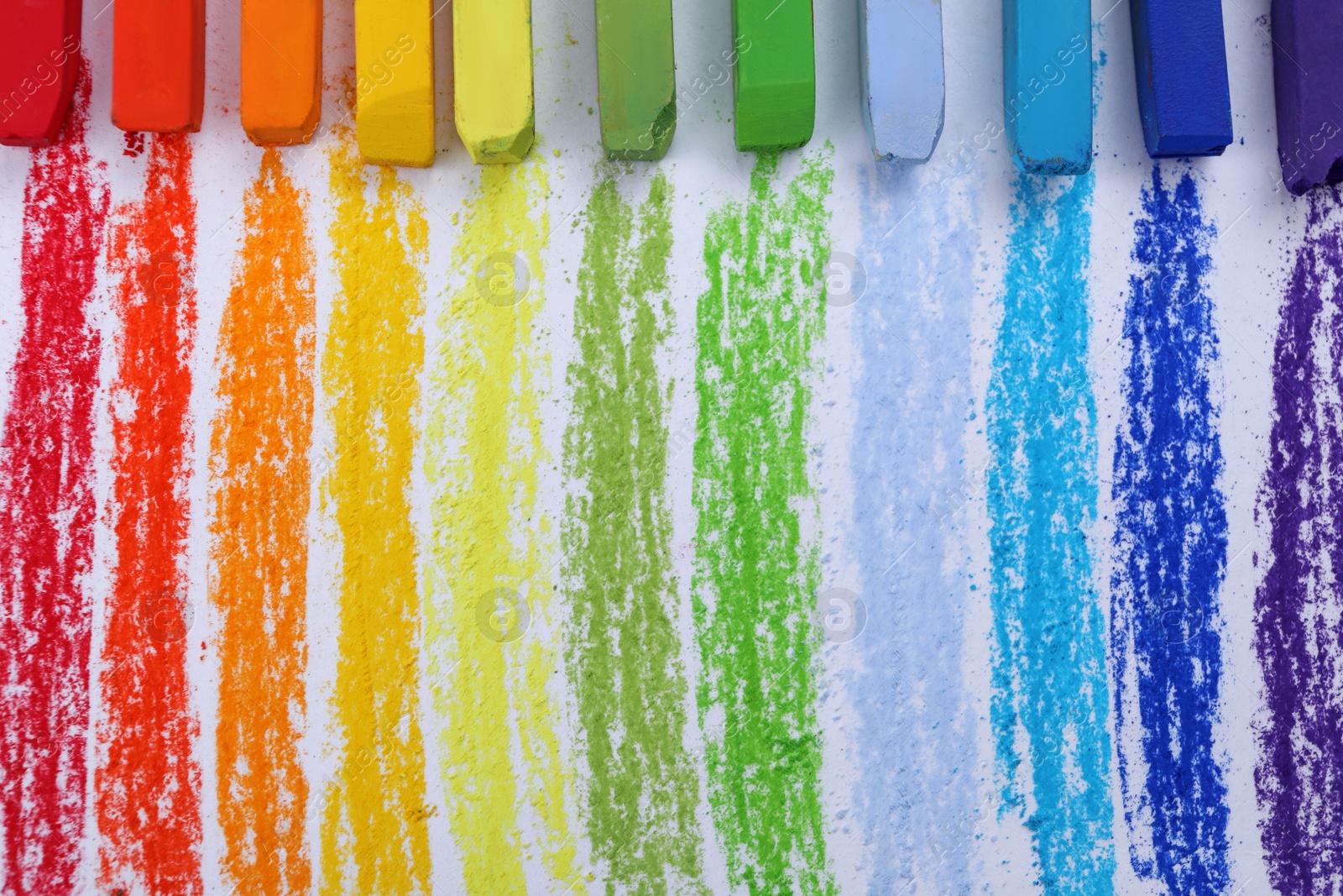 Photo of Colorful pastel chalks on white background, flat lay. Drawing materials